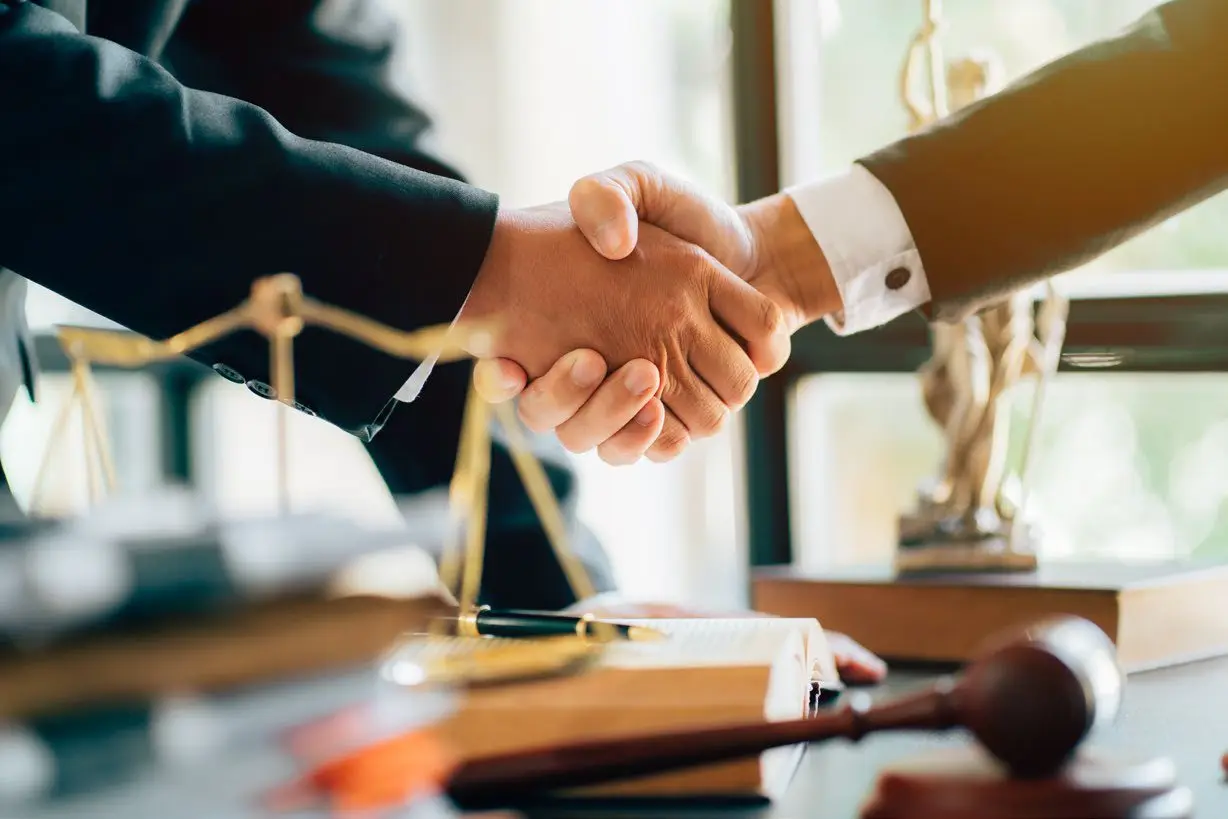 A handshake beside the scales of justice